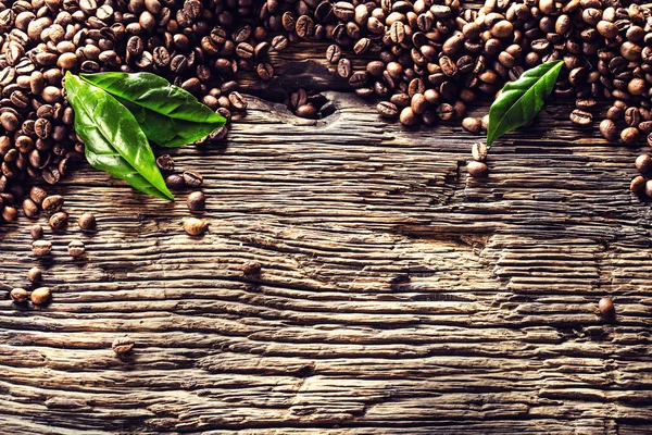 Top of view grains de café et feuilles vertes sur table en chêne rustique — Photo