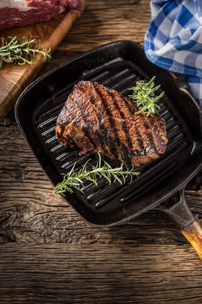 Grilled beef steak in grill pan with herbs rosemary on wooden table — Stock Photo, Image