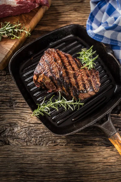 Filete de ternera a la parrilla en sartén con hierbas romero sobre mesa de madera —  Fotos de Stock