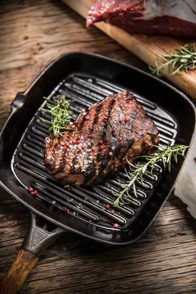 Bistecca di manzo alla griglia in padella con rosmarino alle erbe sul tavolo di legno — Foto Stock