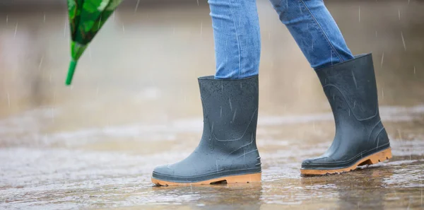 Ragazza piedi in stivali di gomma con ombrello sotto la pioggia in pozzanghera — Foto Stock