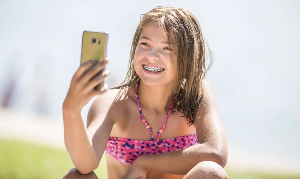 Happy young girl with dental braces making selfhie on beach in s — Stock Photo, Image