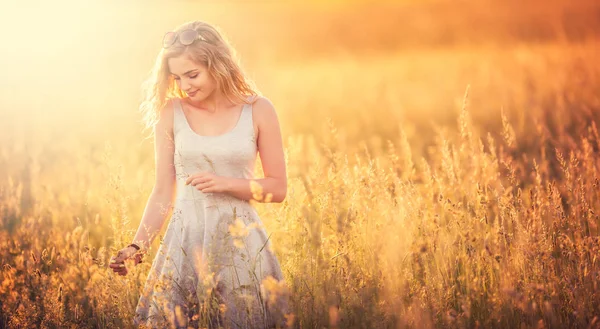 Hermosa chica joven rubia tierna de pie en el prado de verano en — Foto de Stock
