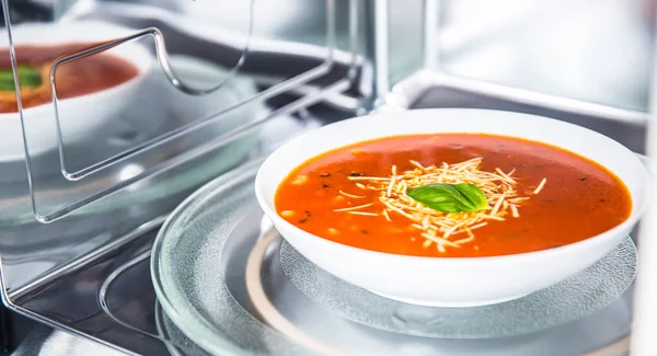 Inside view of new clean staniless microwave oven with a tomato soup in white plate — Stock Photo, Image