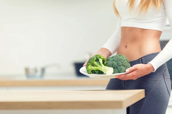 Mujer joven con figura deportiva en la cocina sosteniendo en su han —  Fotos de Stock