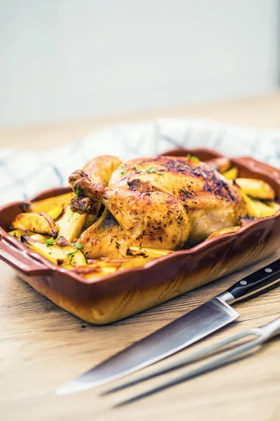 Roasted whole chicken with potatoes in baking dish. Tasty food at home on the kitchen counter — Stock Photo, Image