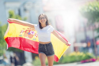 Mutlu kız turist İspanyol bayrağı ile sokakta yürüyor