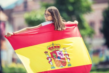 Mutlu kız turist İspanyol bayrağı ile sokakta yürüyor