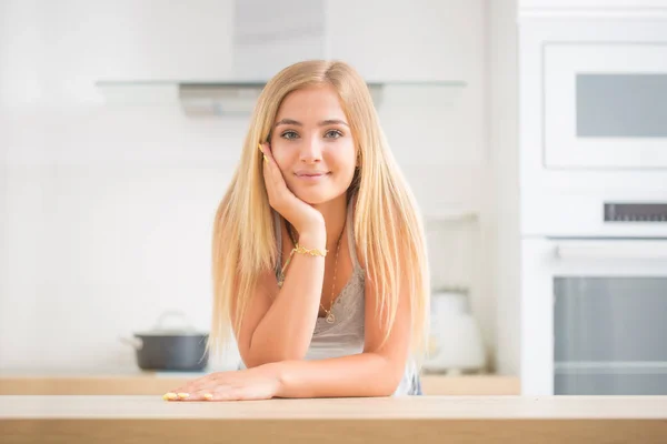 Joven chica rubia alegre en la cocina de la casa. Ella piensa qué —  Fotos de Stock