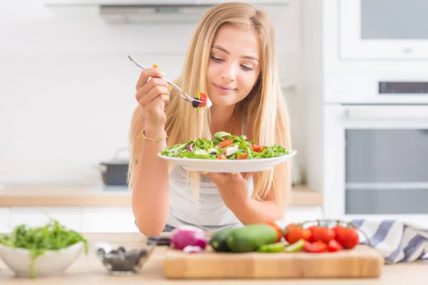 Joven chica rubia feliz comiendo ensalada saludable de rúcula espinaca —  Fotos de Stock