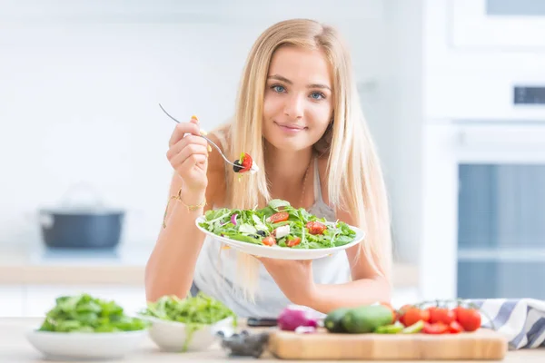 Joven chica rubia feliz comiendo ensalada saludable de rúcula espinaca —  Fotos de Stock