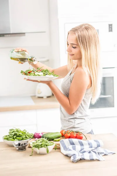 Joven chica rubia feliz comiendo ensalada saludable de rúcula espinaca —  Fotos de Stock