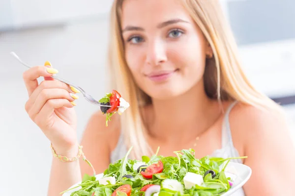 Joven chica rubia feliz comiendo ensalada saludable de rúcula espinaca — Foto de Stock