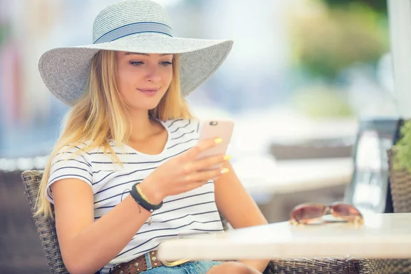 Młoda piękna kobieta siedzi w kawiarni i za pomocą smartfona — Zdjęcie stockowe