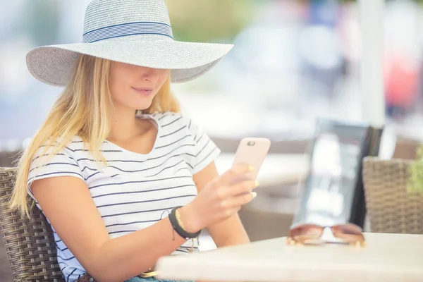 Kafede oturan ve akıllı telefon kullanan genç güzel kadın — Stok fotoğraf