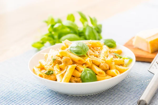 Pasta penne com pedaços de frango cogumelos manjericão queijo parmesão e vinho branco. Comida italiana em prato branco na mesa da cozinha — Fotografia de Stock