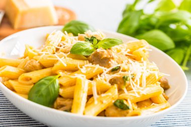 Tavuk parçaları mantar fesleğen parmesan peyniri ve beyaz şarap ile Makarna penne. Mutfak masasında beyaz tabakta İtalyan yemekleri