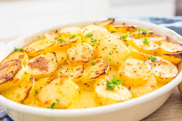 Batatas assadas com especiarias e ervas na mesa da cozinha — Fotografia de Stock