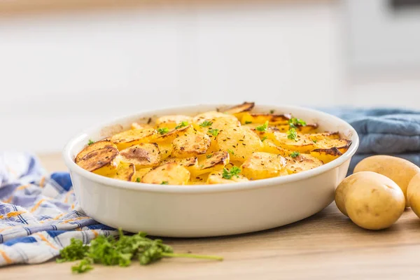 Roasted potatoes with spices and herbs on kitchen table — Stock Photo, Image