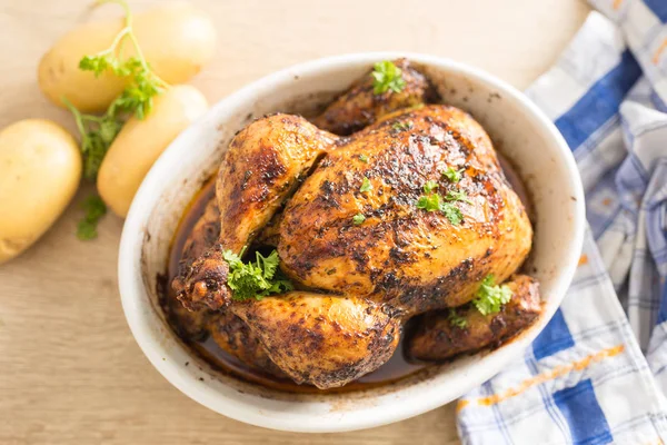 Geroosterde hele kip in de kom met aardappelen op huis keuken tafel-bovenaanzicht — Stockfoto