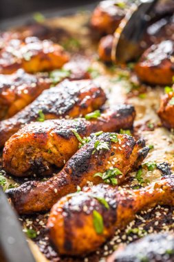Pişmiş kağıt üzerinde baharat otlar ve susam ile ızgara hicken bacaklar BBQ. Kavurucu çanak kavrulmuş kümes hayvanları yemek