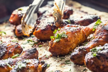 Pişmiş kağıt üzerinde baharat otlar ve susam ile ızgara hicken bacaklar BBQ. Kavurucu çanak kavrulmuş kümes hayvanları yemek
