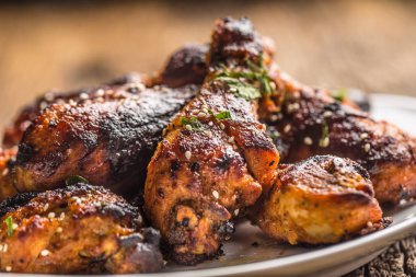 Pişmiş kağıt üzerinde baharat otlar ve susam ile ızgara hicken bacaklar BBQ. Beyaz plaka üzerinde kavrulmuş kümes hayvanları yemeği