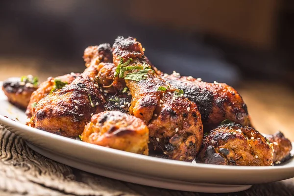 Patas de pollo a la parrilla barbacoa con especias hierbas y sésamo sobre papel cocido. Harina de ave asada en plato blanco — Foto de Stock