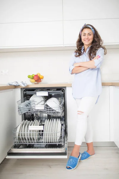 Giovane donna che utilizza una lavastoviglie nella sua cucina moderna — Foto Stock