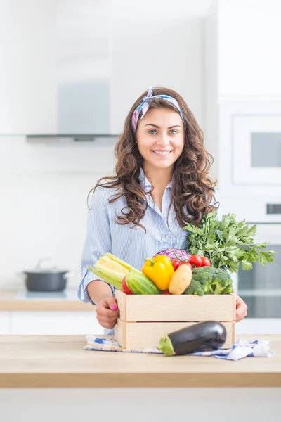 有機野菜でいっぱいの木箱を持つ彼女の台所の女性 — ストック写真