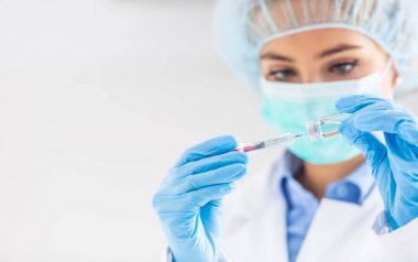 Şırınga iğnesi ve medicin ampulü ile çalışan kadın doktor