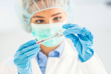 Şırınga iğnesi ve medicin ampulü ile çalışan kadın doktor