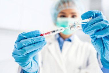 Şırınga iğnesi ve medicin ampulü ile çalışan kadın doktor