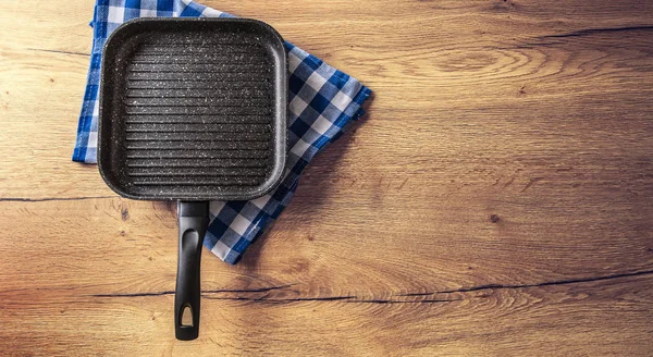 Kerámia grill Pan a konyhában, fából készült asztal, kék kockás ta — Stock Fotó