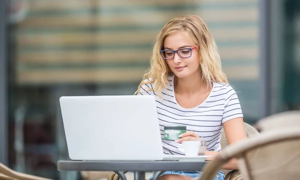 Молодая блондинка с кредиткой и ноутбуком — стоковое фото