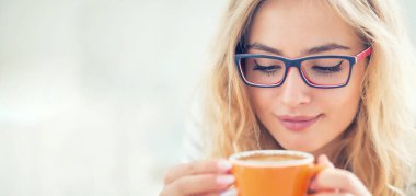 Mutlu genç kadının elinde bir fincan kahve. 