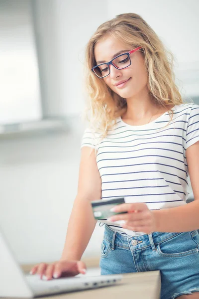 Молода блондинка тримає кредитну картку і використовує ноутбук — стокове фото