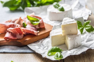 Camembert veya brie peynir ve domuz jambonprosciutto masada fesleğen yaprakları ile