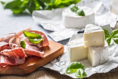 Camembert veya brie peynir ve domuz jambonprosciutto masada fesleğen yaprakları ile