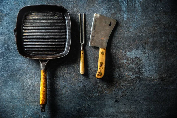 Carnicero de parrilla vintage y tenedor en mesa de hormigón oscuro — Foto de Stock