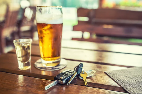 Llaves de coche y vaso de cerveza o alcohol destilado sobre la mesa en un pub o restaurante — Foto de Stock