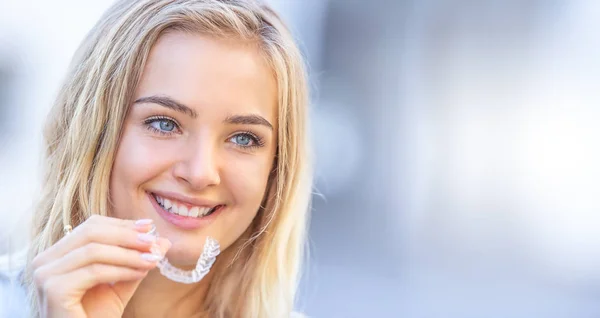 Invisalign ortodonti kavramı - Genç çekici kadın holding
