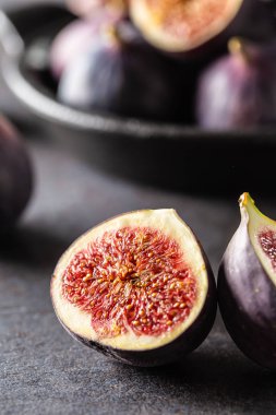 Koyu beton masa üzerinde siyah bir kapta birkaç incir