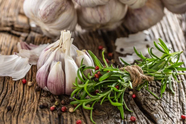 Knoflookteentjes bol met verse rozemarijn en specerijen op oude houten tafel — Stockfoto