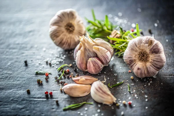 Aglio spicchi e bulbo con rosmarino fresco sale e spezie sulla tavola di cemento — Foto Stock