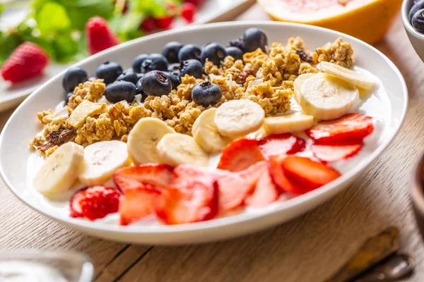 Zdrowe śniadanie serwowane z talerz jogurtu musli jagody truskawki i Banana. — Zdjęcie stockowe