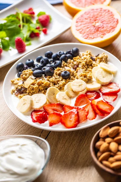 Café da manhã saudável servido com prato de iogurte muesli mirtilos morangos e banana . — Fotografia de Stock
