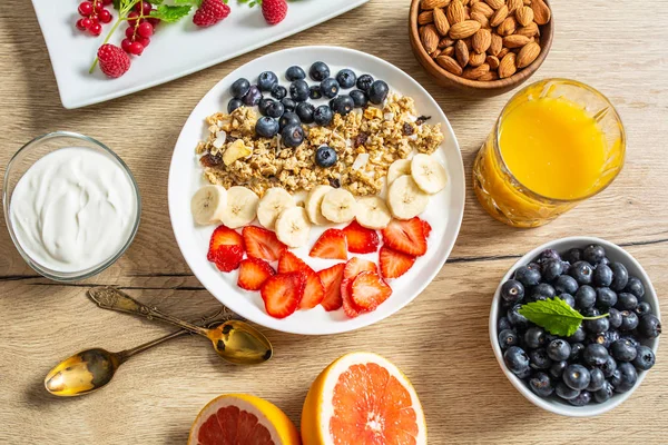 Café da manhã saudável servido com prato de iogurte muesli mirtilos morangos e banana . — Fotografia de Stock