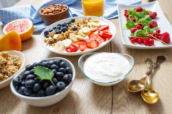 Desayuno saludable servido con un plato de yogur muesli arándanos fresas y plátano . — Foto de Stock