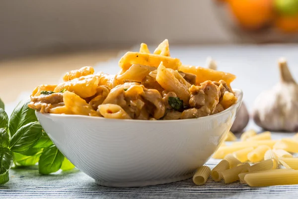 Pasta penne com pedaços de frango cogumelos manjericão e queijo parmesão Comida italiana em tigela branca na mesa da cozinha — Fotografia de Stock